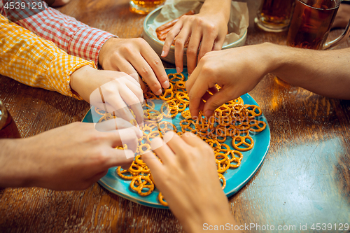 Image of people, leisure, friendship and communication concept - happy friends drinking beer, talking and clinking glasses at bar or pub