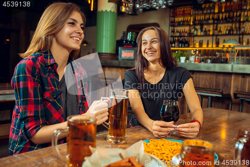 Image of people, leisure, friendship and communication concept - happy friends drinking beer, talking and clinking glasses at bar or pub