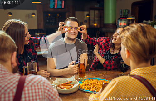 Image of people, leisure, friendship and communication concept - happy friends drinking beer, talking and clinking glasses at bar or pub