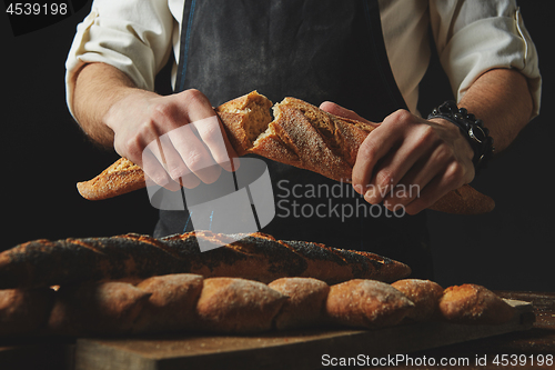 Image of Male hands break the baguette