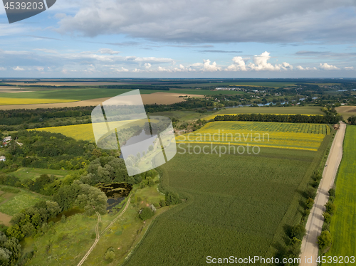 Image of Panoramic view from drone to the countryside with a river, dirt road and agricultural fields against cloudy sky