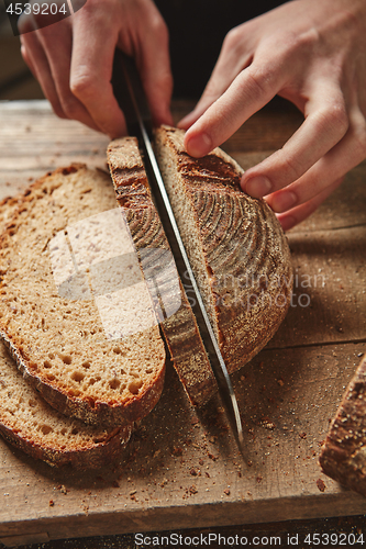 Image of Male hands slicing homemade bread