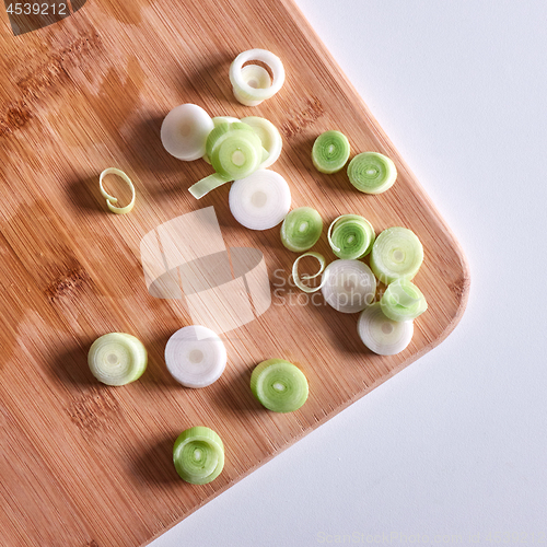 Image of Sliced leek onions on a wooden board on a gray background with copy space. Flat lay