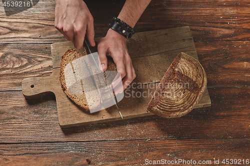 Image of Man slicing tasty fresh bread.