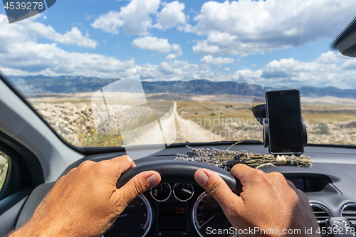 Image of Detail of male driver hands on steering wheel. Driving a car on country road. View from the cabin trough the windshield.