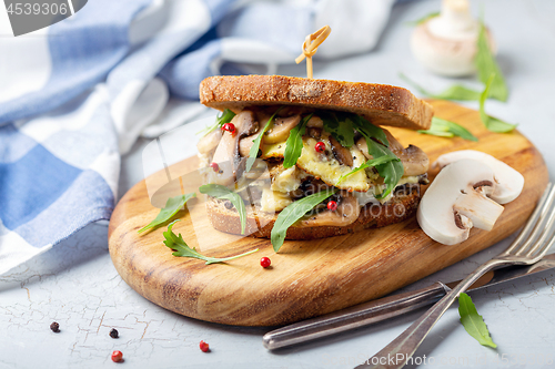Image of Mushroom sandwich with scrambled eggs and arugula.