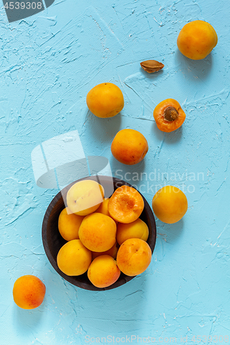 Image of Ripe apricots in a black wooden bowl.