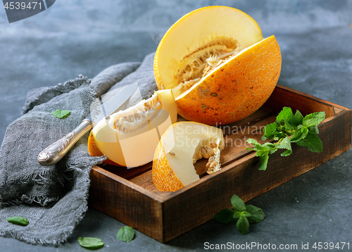 Image of Slices of ripe yellow melon in a wooden tray.