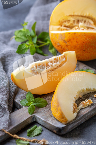 Image of Slices of ripe yellow melon on a wooden board.