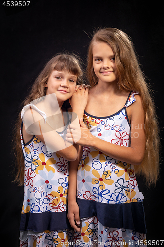 Image of Two sisters of different ages on a black background