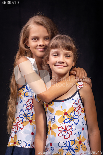 Image of Portrait of two friendly sisters on a black background