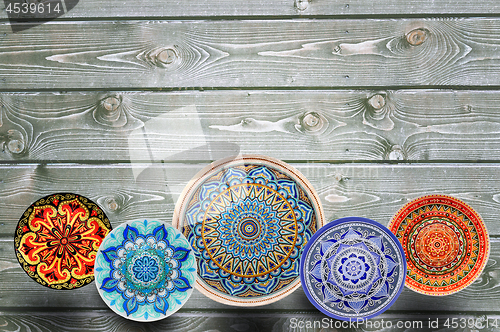 Image of Set of decorative ceramic plates hand painted dot pattern with acrylic paints on a gray wooden background. Copy space.