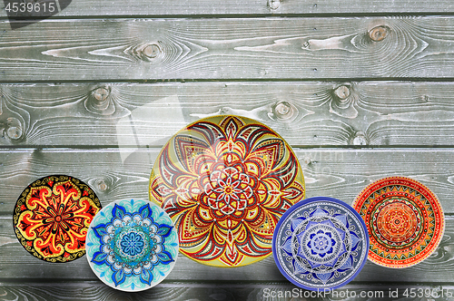 Image of Set of decorative ceramic plates hand painted dot pattern with acrylic paints on a gray wooden background. Copy space.