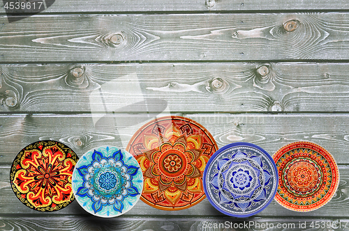 Image of Set of decorative ceramic plates hand painted dot pattern with acrylic paints on a gray wooden background. Copy space.