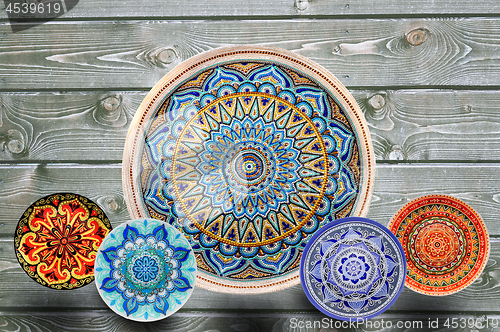 Image of Set of decorative ceramic plates hand painted dot pattern with acrylic paints on a gray wooden background. Copy space.