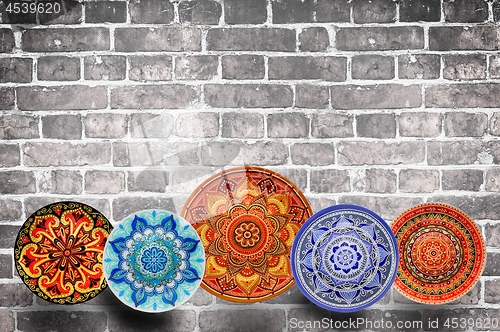 Image of Set of decorative ceramic plates hand painted dot pattern with acrylic paints on a gray wooden background. Copy space.