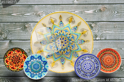 Image of Set of decorative ceramic plates hand painted dot pattern with acrylic paints on a gray wooden background. Copy space.