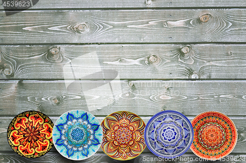 Image of Set of decorative ceramic plates hand painted dot pattern with acrylic paints on a gray wooden background. Copy space.