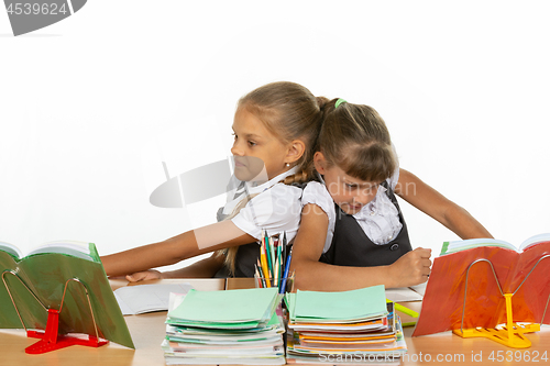 Image of Two girls share a desk and push each other\'s backs