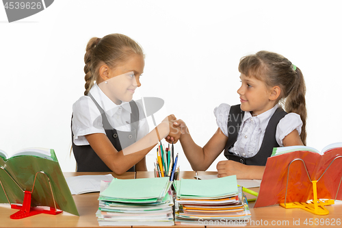 Image of Two girls at a desk shake hands