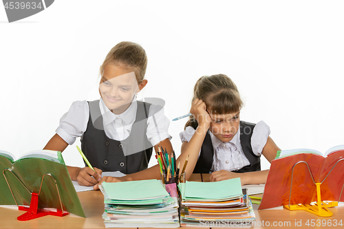 Image of Two schoolgirls at a desk, one excellent student, the second two-year student