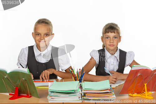 Image of Two schoolgirls gaze intently and emotionlessly into the frame