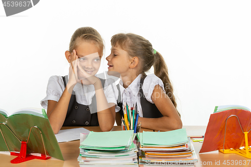 Image of Girlfriend at school desk tells something interesting on the ear