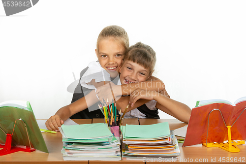 Image of Two schoolgirls are sitting at a desk looking at textbooks