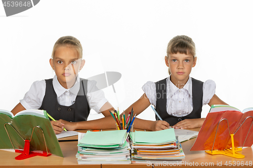 Image of Two schoolgirls gaze intently and emotionlessly into the frame