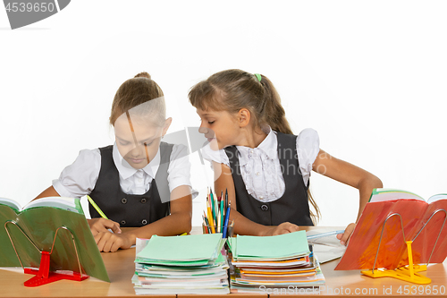 Image of Girl looks at what her desk neighbor writes in a notebook