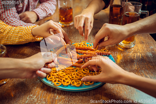 Image of people, leisure, friendship and communication concept - happy friends drinking beer, talking and clinking glasses at bar or pub