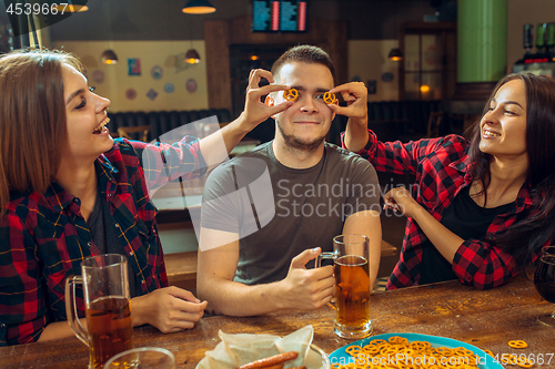 Image of people, leisure, friendship and communication concept - happy friends drinking beer, talking and clinking glasses at bar or pub