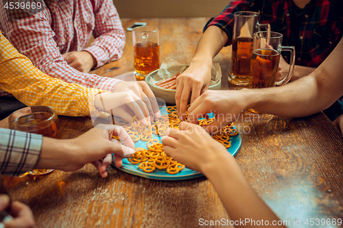 Image of people, leisure, friendship and communication concept - happy friends drinking beer, talking and clinking glasses at bar or pub