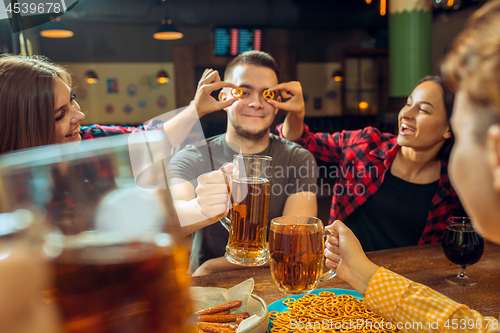 Image of people, leisure, friendship and communication concept - happy friends drinking beer, talking and clinking glasses at bar or pub