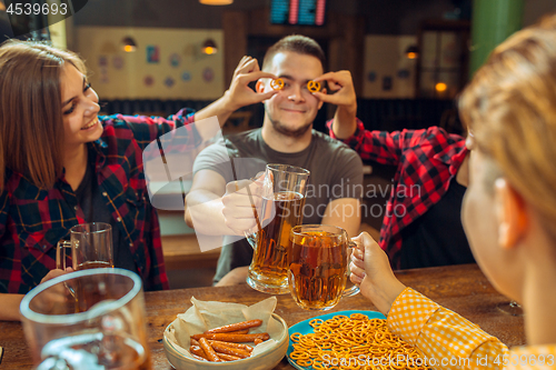 Image of people, leisure, friendship and communication concept - happy friends drinking beer, talking and clinking glasses at bar or pub