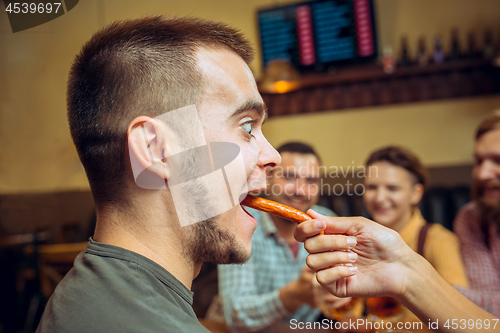 Image of people, leisure, friendship and communication concept - happy friends drinking beer, talking and clinking glasses at bar or pub