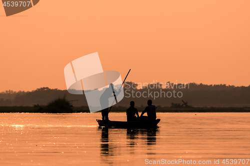 Image of Men in a boat on a river silhouette