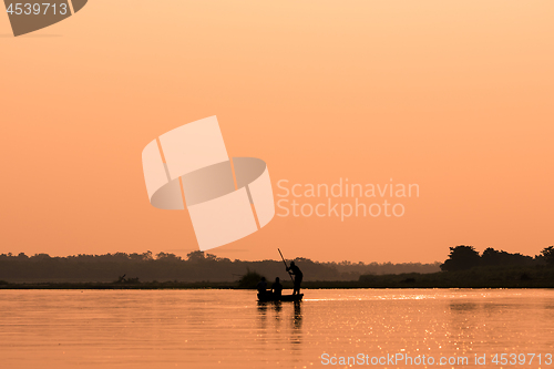 Image of Men in a boat on a river silhouette