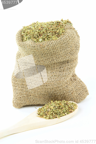 Image of Oregano leaves in burlap bag and over wooden spoon. 