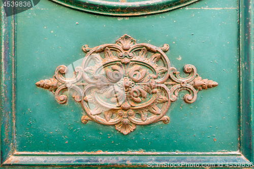 Image of rusty ornamental decoration at a green door in Italy