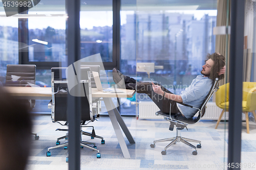 Image of young businessman relaxing at the desk