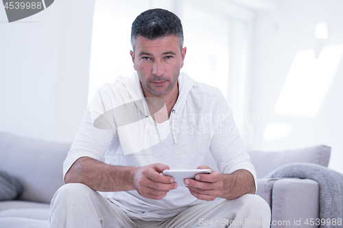 Image of young man using a mobile phone  at home