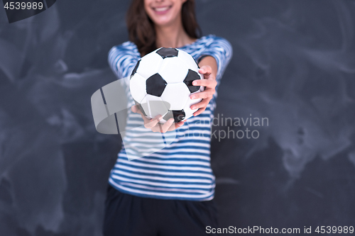 Image of woman holding a soccer ball in front of chalk drawing board