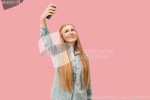 Image of Portrait of a happy smiling casual girl showing blank screen mobile phone isolated over pink background