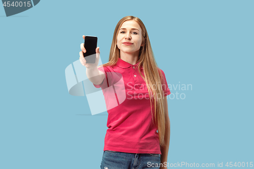 Image of Portrait of a confident casual girl showing blank screen mobile phone isolated over blue background