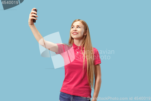 Image of Portrait of a happy smiling casual girl showing blank screen mobile phone isolated over blue background