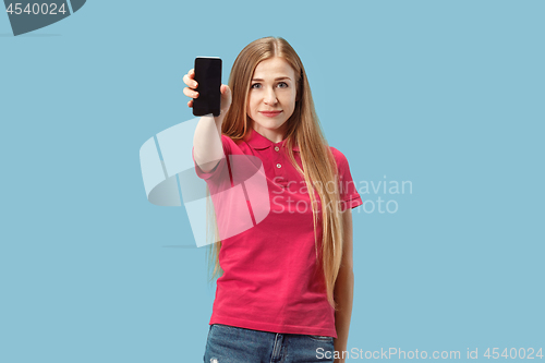 Image of Portrait of a confident casual girl showing blank screen mobile phone isolated over blue background