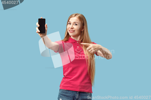 Image of Portrait of a confident casual girl showing blank screen mobile phone isolated over blue background
