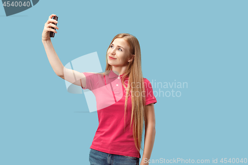 Image of Portrait of a happy smiling casual girl showing blank screen mobile phone isolated over blue background