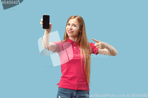 Image of Portrait of a confident casual girl showing blank screen mobile phone isolated over blue background